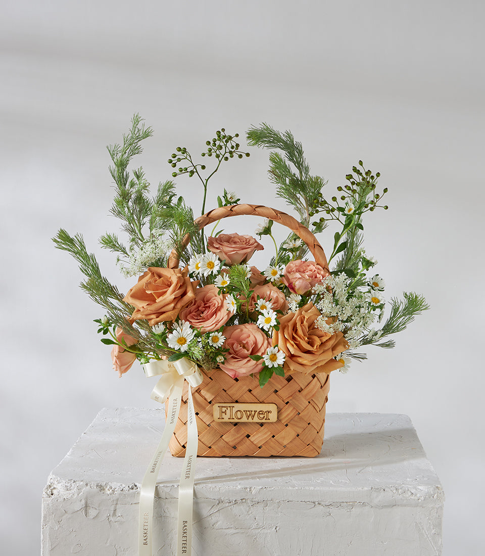Peach and dusty rose flower basket with white daisies, woven wood handle, cream ribbon, birthday gift arrangement