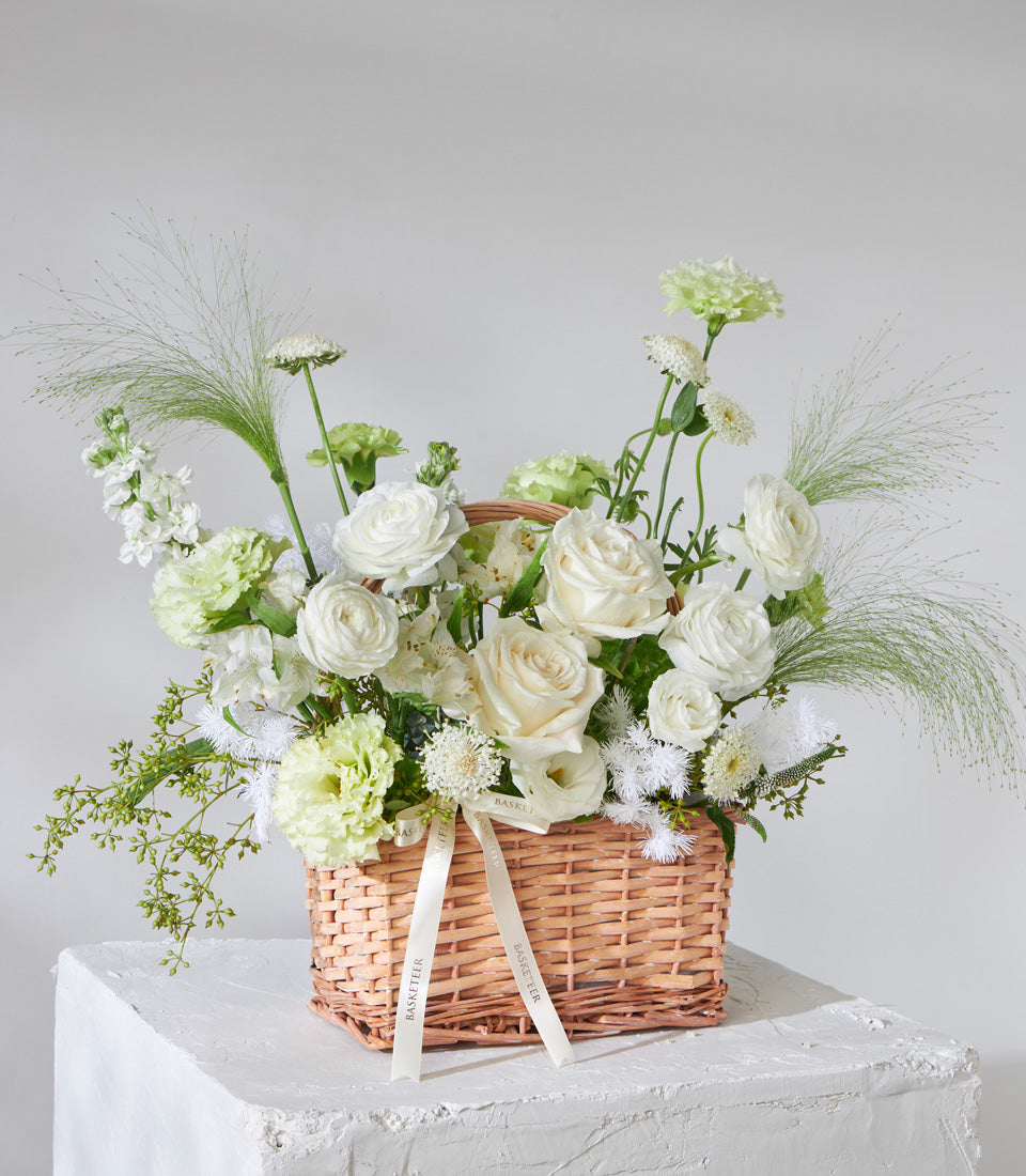Cream and white fresh flower basket with roses, ranunculus, and feathery green foliage for birthdays