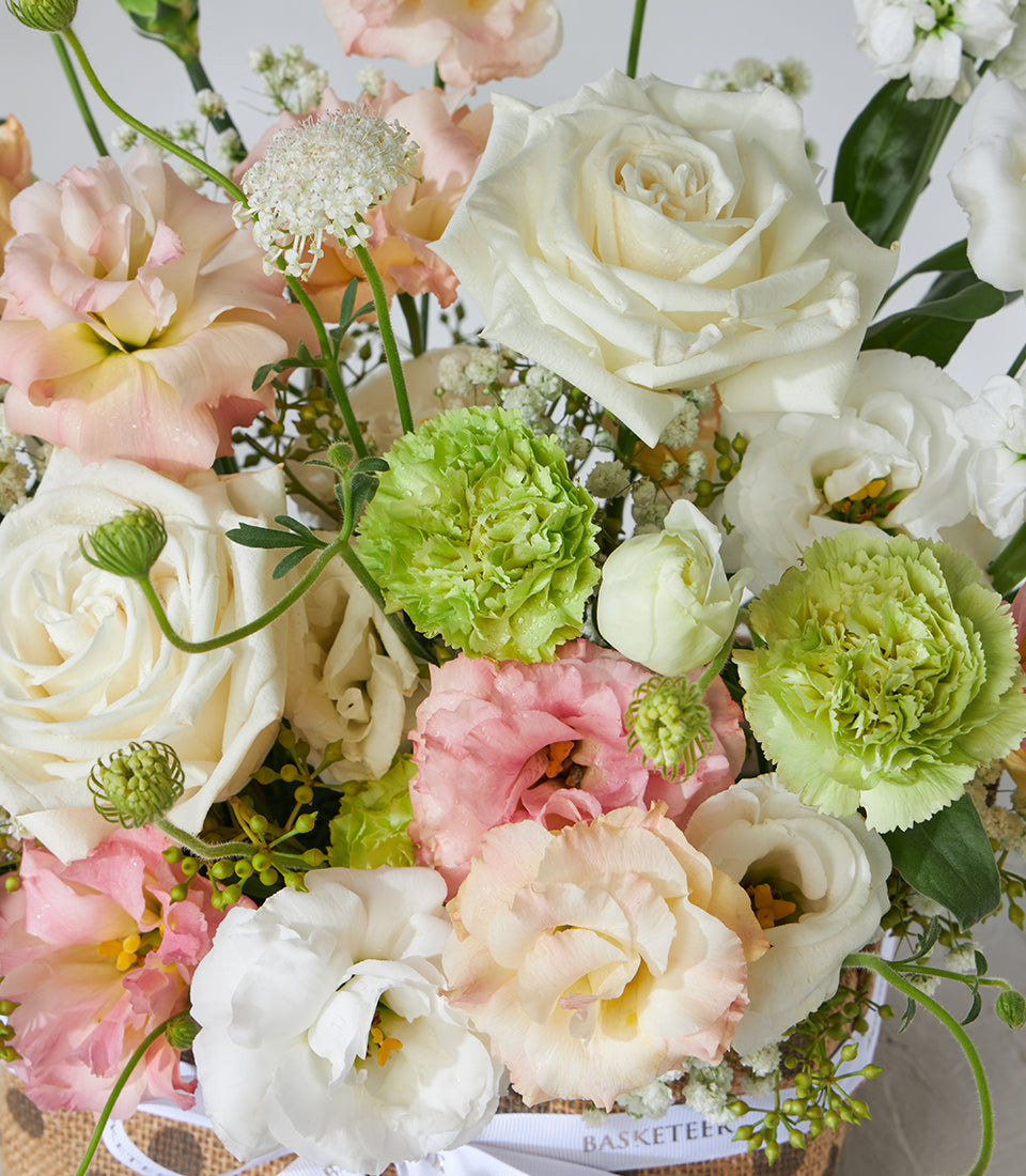 White roses and peach lisianthus pastel flower basket with green carnations and baby's breath