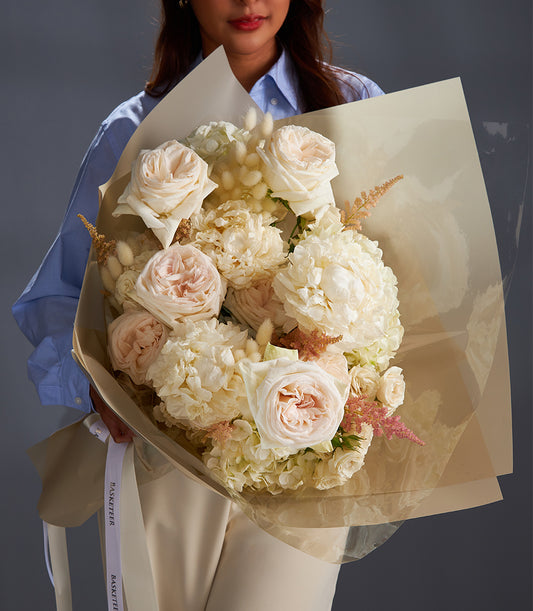 Large white and pale pink rose bouquet with hydrangeas and bunny tail grass, elegantly wrapped with white ribbon