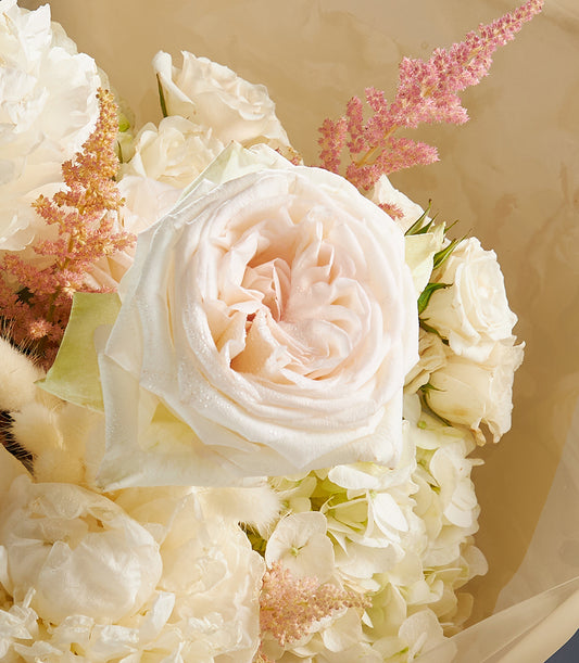 Luxurious white rose and hydrangea bouquet with peach-toned centre rose and pink astilbe accents