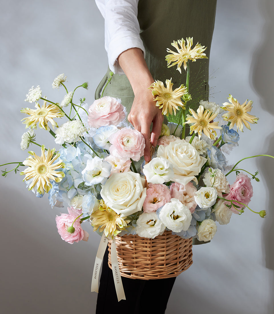 Wicker basket with pastel roses, hydrangeas, and gerbera daisies for birthday celebrations