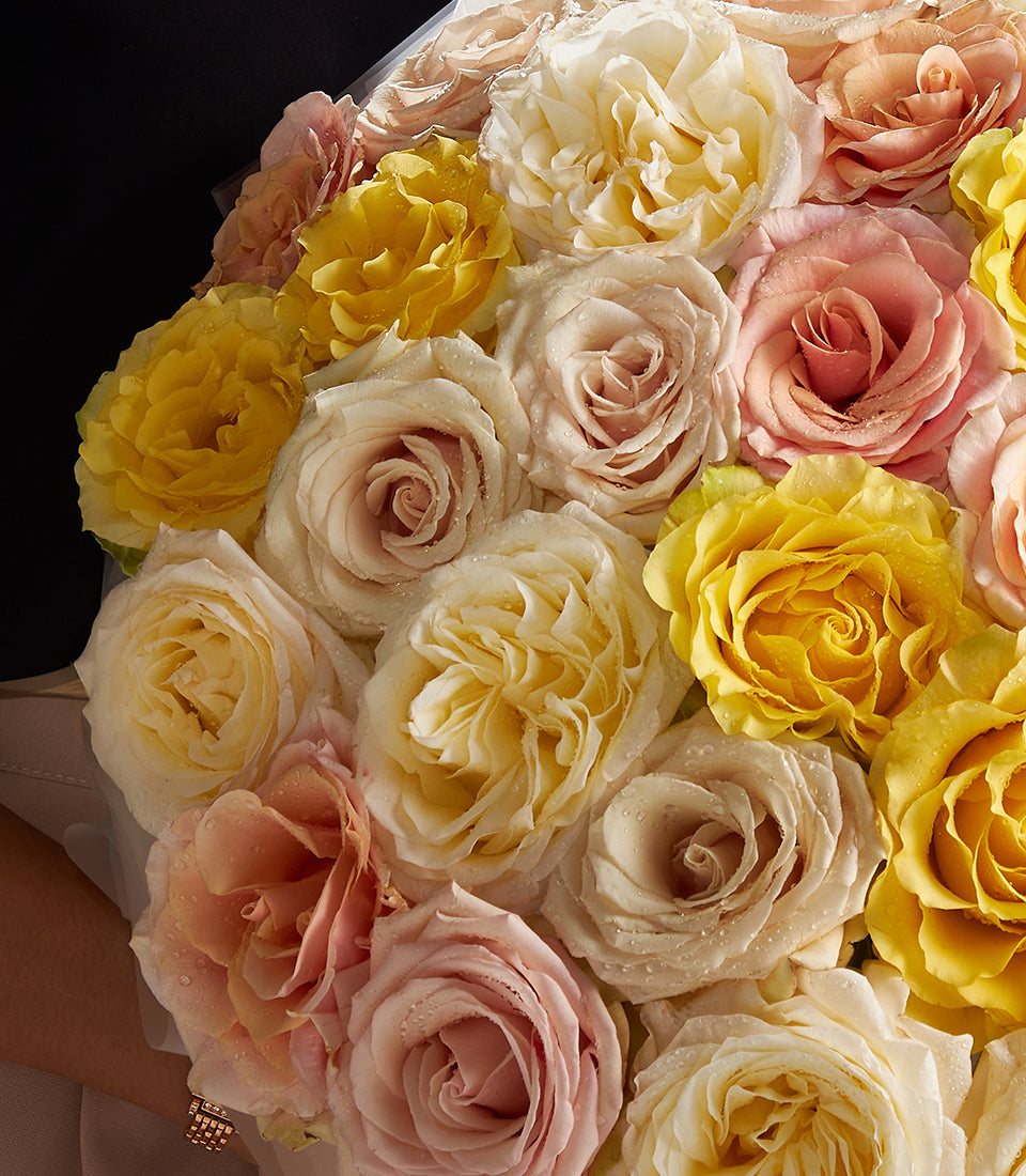 Premium rose bouquet in yellow, cream, and peach tones with fresh-cut blooms and glistening petals