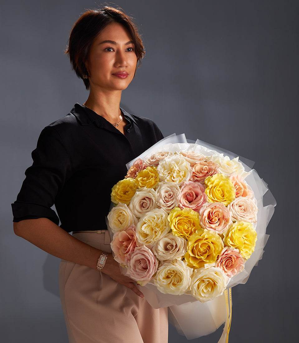 Elegant mixed rose bouquet in yellow, pink and cream with white paper wrap and yellow ribbon