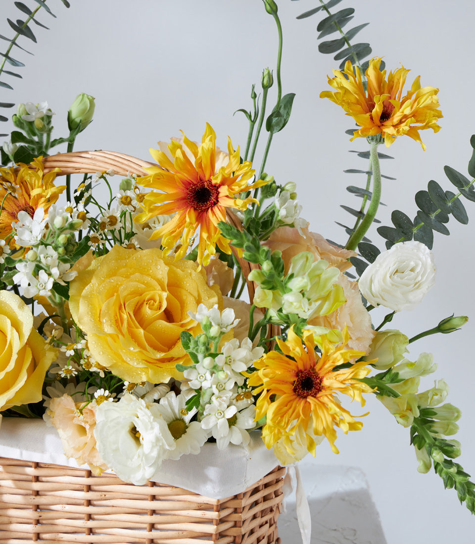 Vibrant yellow and white flower basket with roses, gerberas, and ranunculus for birthday celebrations