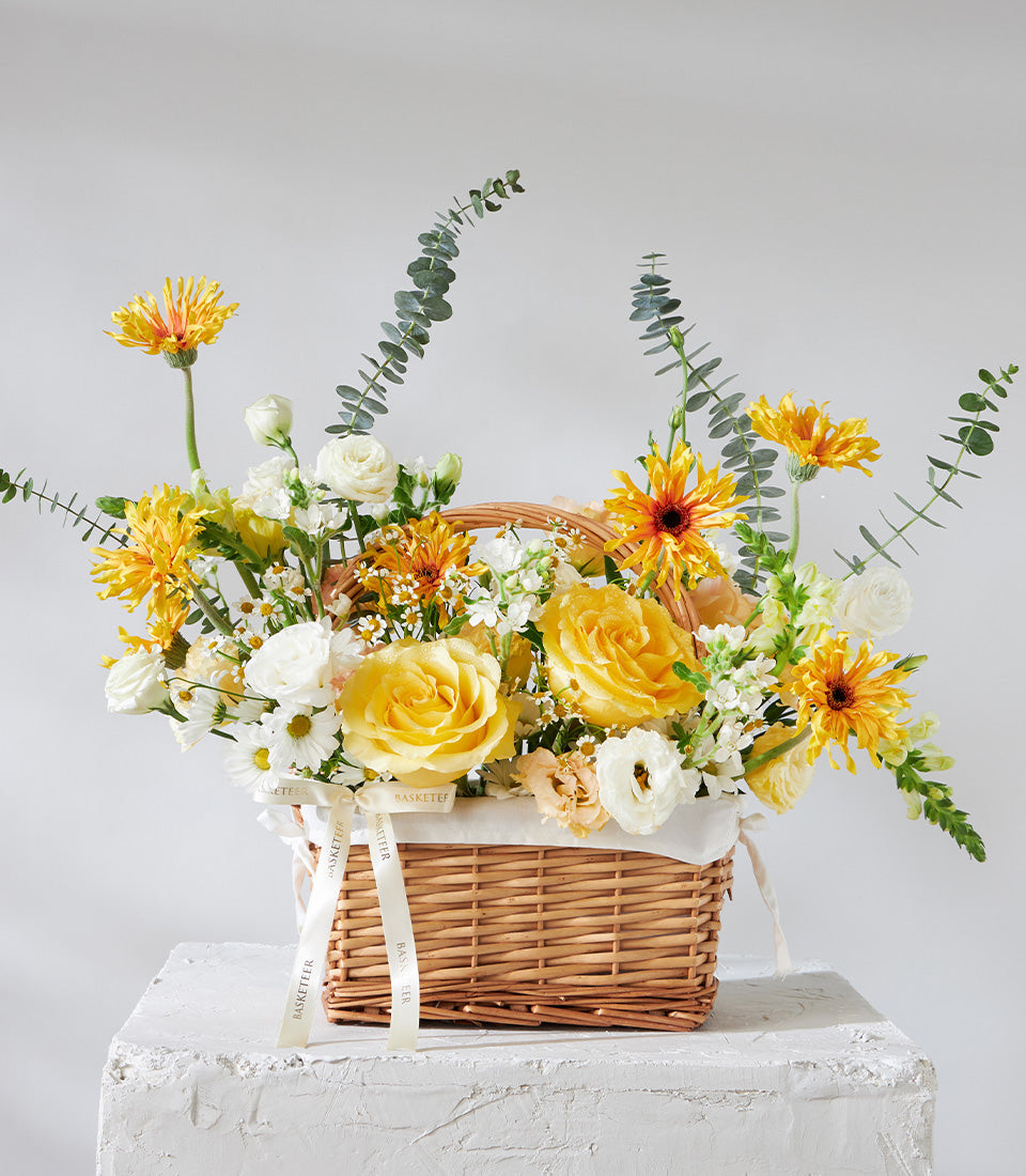 Yellow and white rose basket with eucalyptus greenery and woven wicker for birthday celebrations