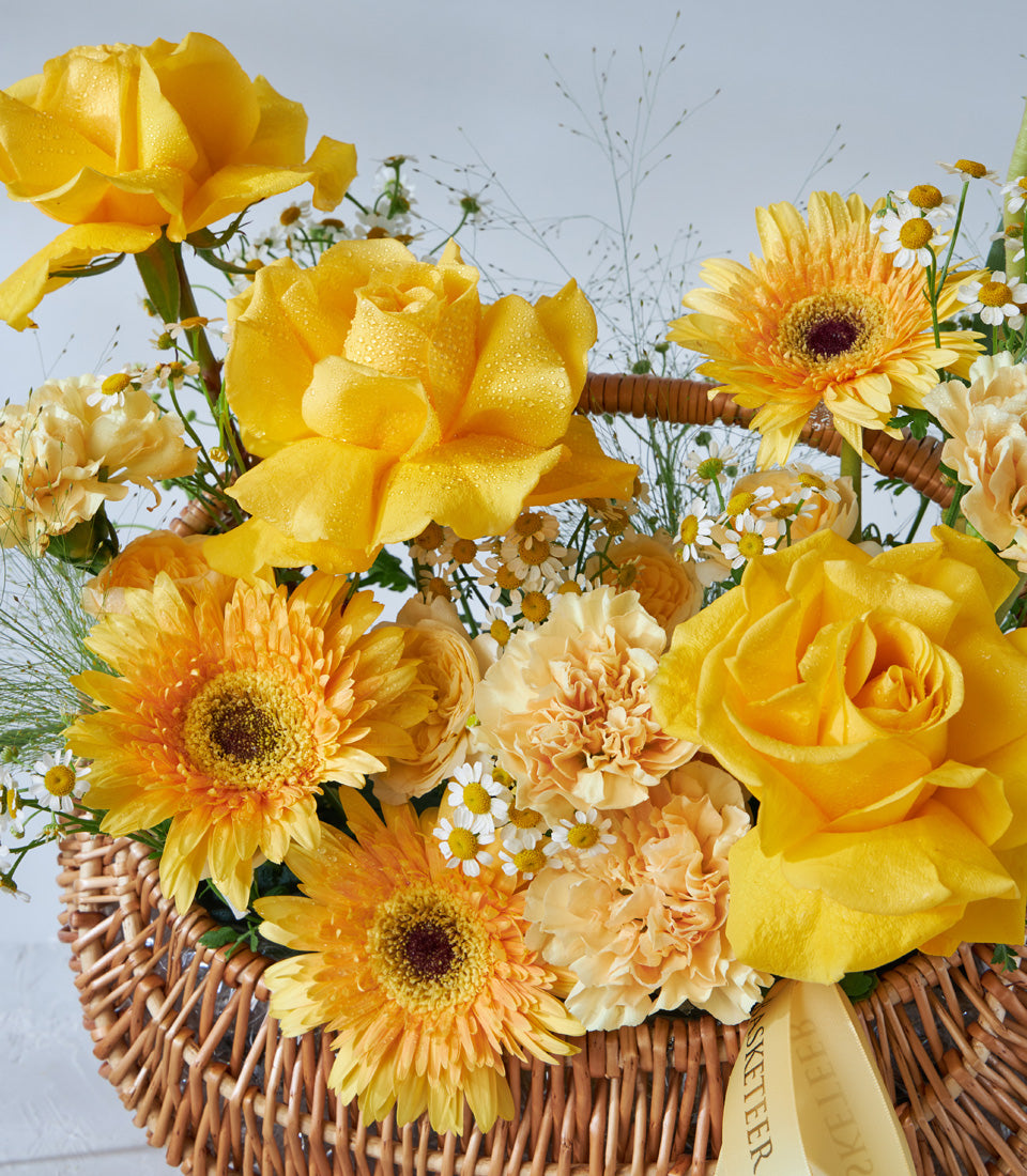 Golden yellow roses and cream daisies in woven wicker basket, fresh birthday flower gift