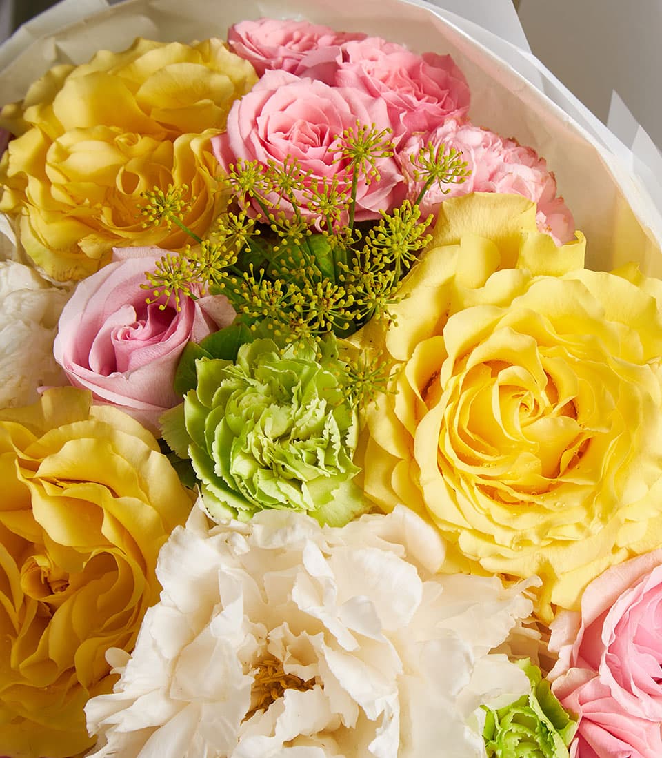 Premium mixed bouquet with golden yellow and blush roses, white peonies, and green carnations in fresh arrangement