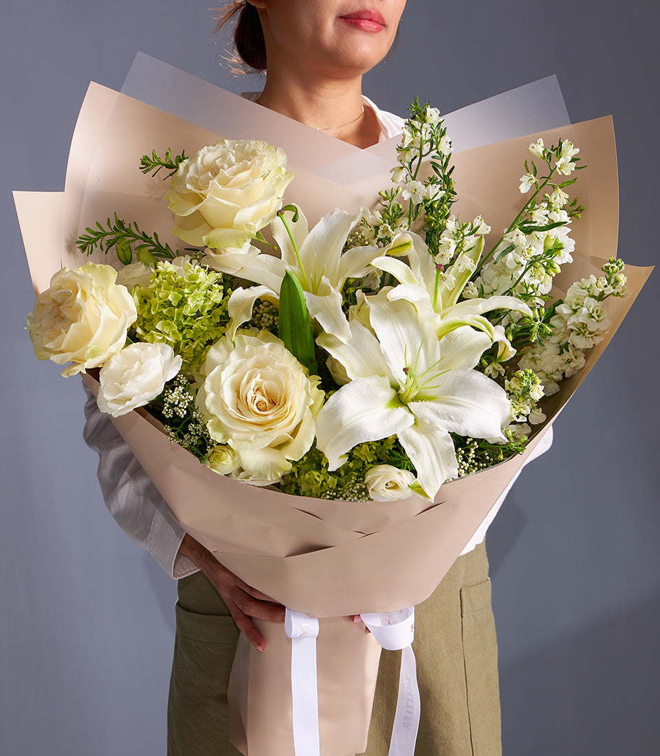 Premium white roses and lilies bouquet with green hydrangeas, beige wrap and white ribbon