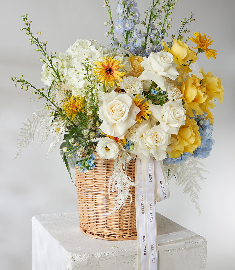 Premium white and yellow rose basket with blue hydrangeas and delicate ferns