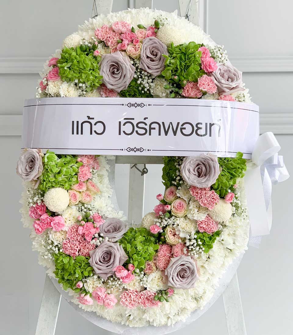 Pastel funeral wreath with white chrysanthemums, pink carnations, grey roses, and hydrangeas on easel