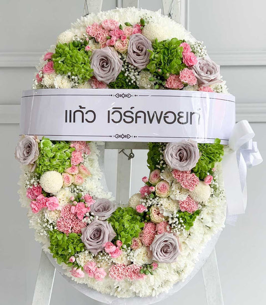 Pastel funeral wreath with white chrysanthemums, pink carnations, grey roses, and hydrangeas on easel