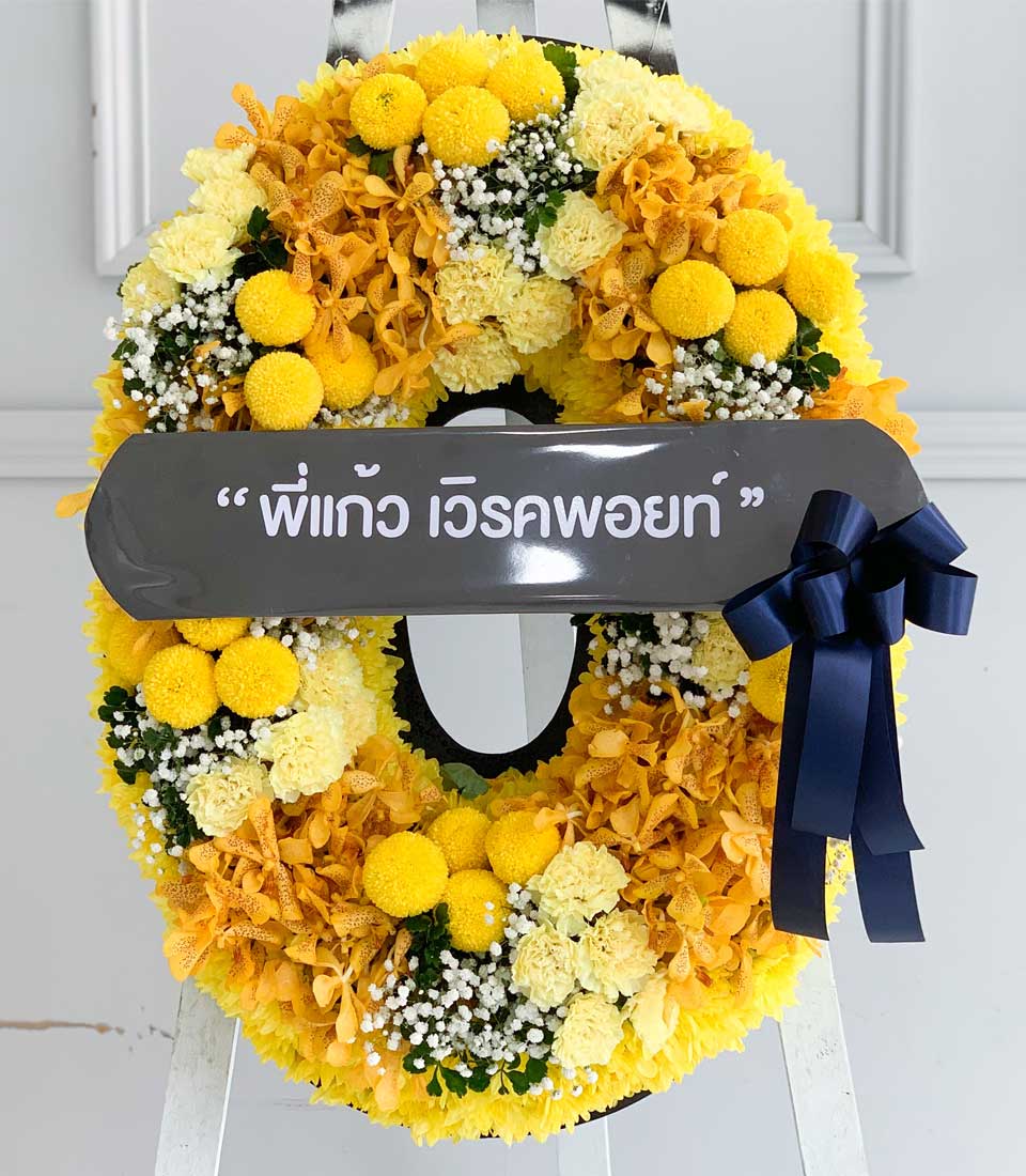 Yellow and orange floral wreath with chrysanthemums, carnations, orchids, and baby's breath on white easel
