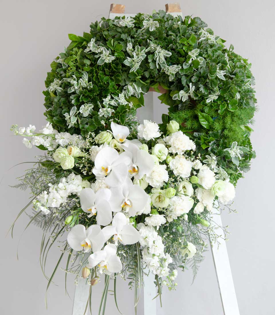 Serene Farewell Petals Wreath with white orchids, carnations, and lush green foliage sympathy arrangement