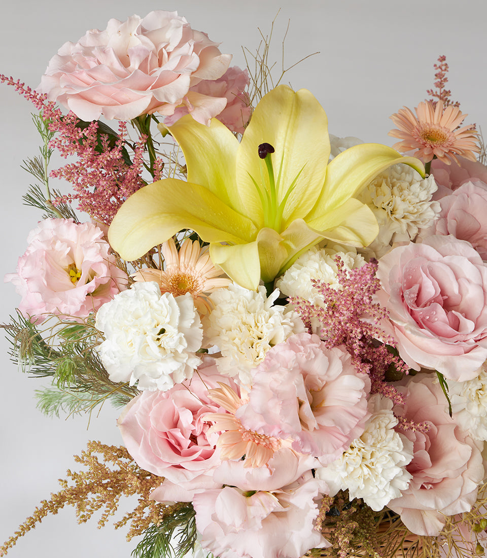 Vibrant yellow lily and pink rose basket bouquet with lisianthus, carnations, and gerbera daisies