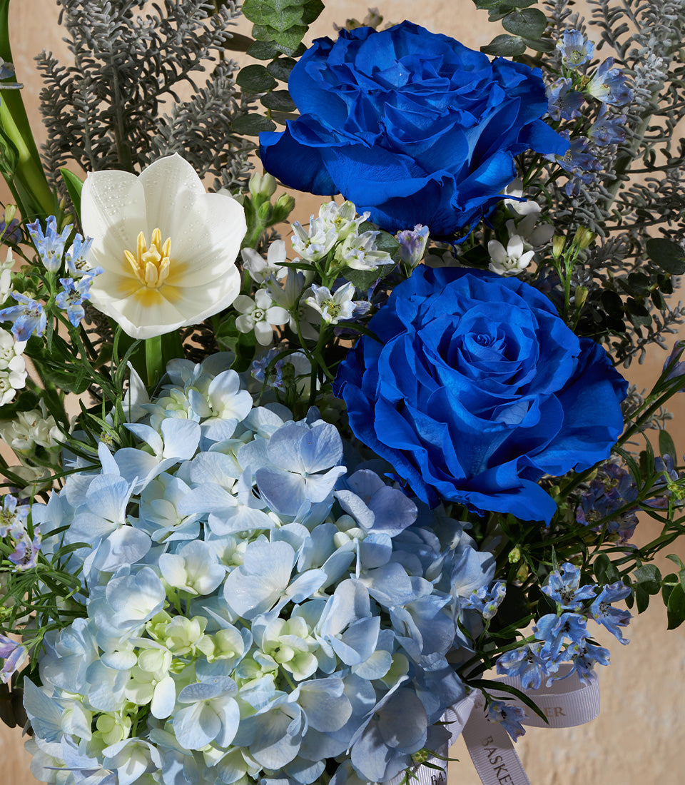 Royal blue roses and white tulips with light blue hydrangeas in elegant vase arrangement
