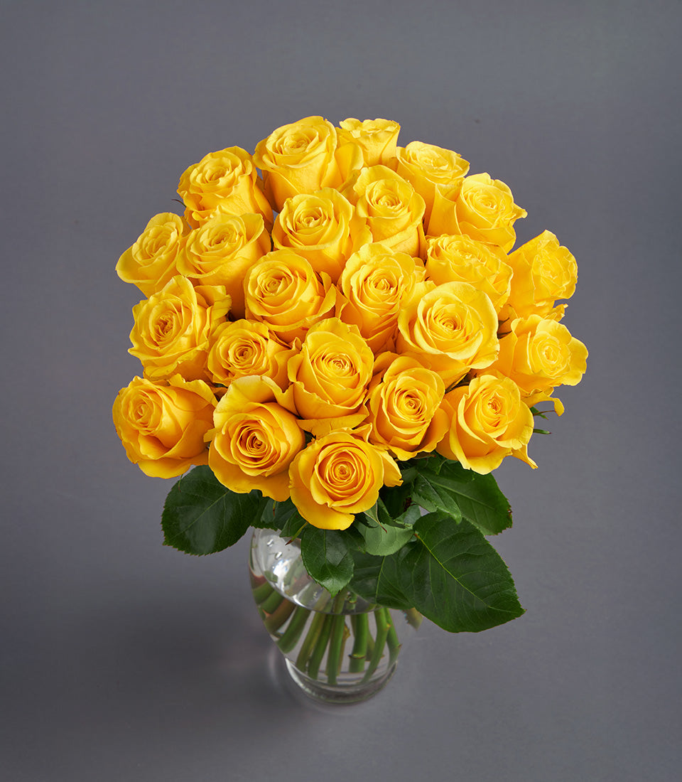 A stunning, vibrant yellow rose bouquet with fresh green foliage, elegantly arranged in