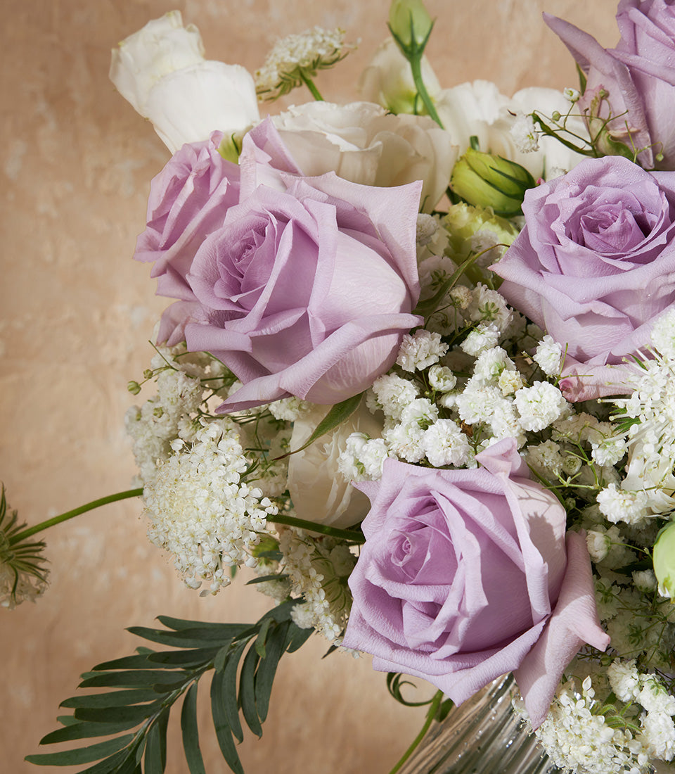 Lavender roses with white baby's breath in clear glass vase arrangement