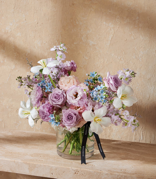 Ethereal lavender floral arrangement with roses, lisianthus, and forget-me-nots in clear glass vase