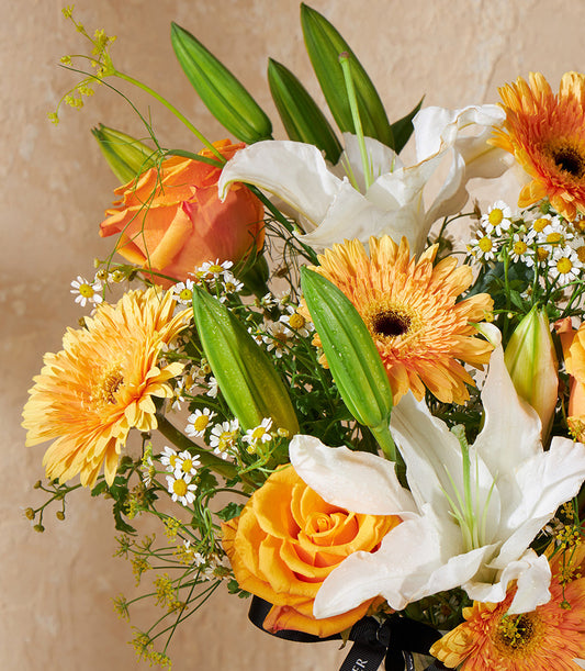 Sunlit Grace vibrant floral arrangement with orange gerberas, yellow roses, white lilies, and filler flowers