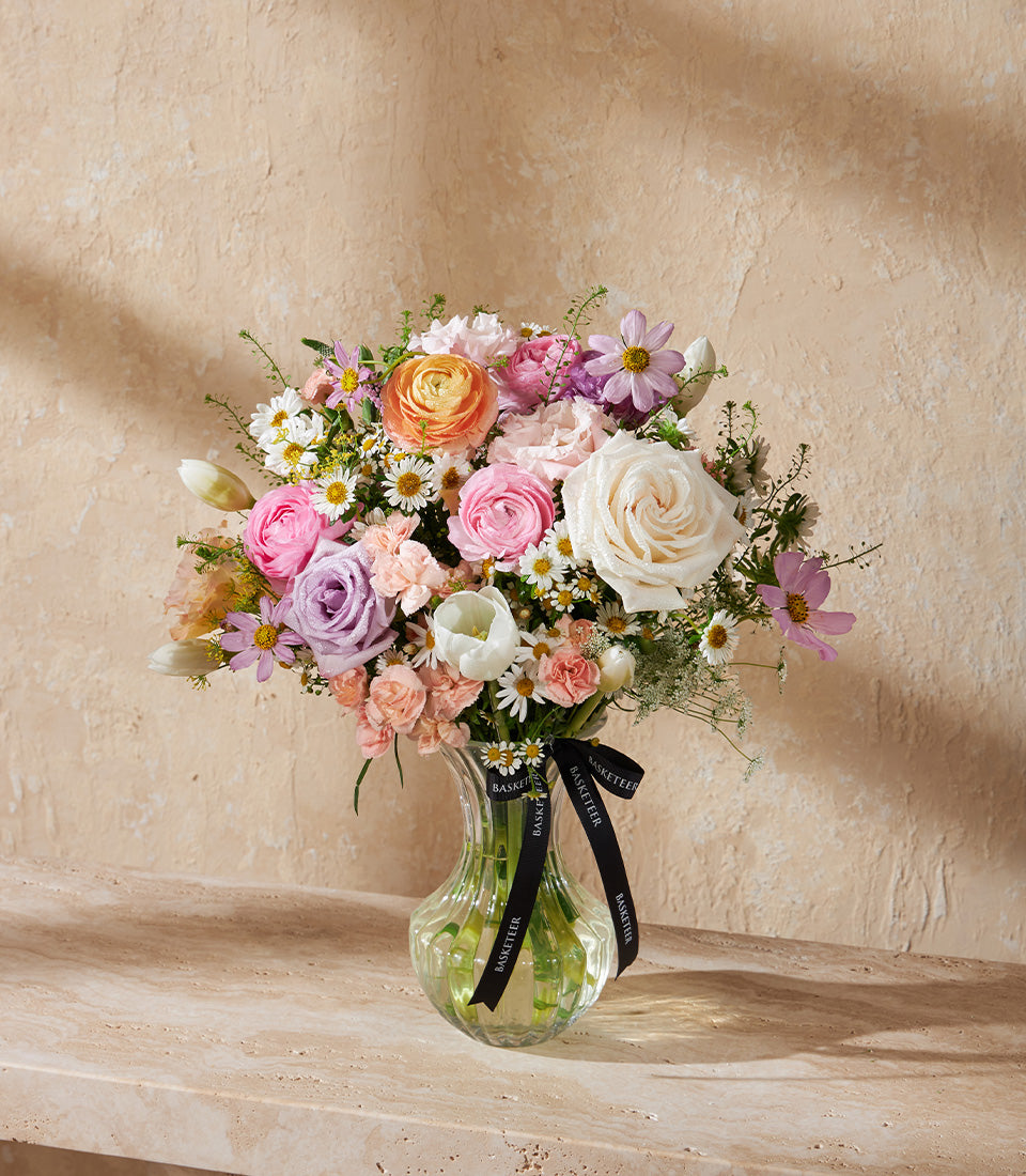 Pastel Bloom Symphony fresh flower arrangement in clear glass vase with roses, ranunculus, and tulips