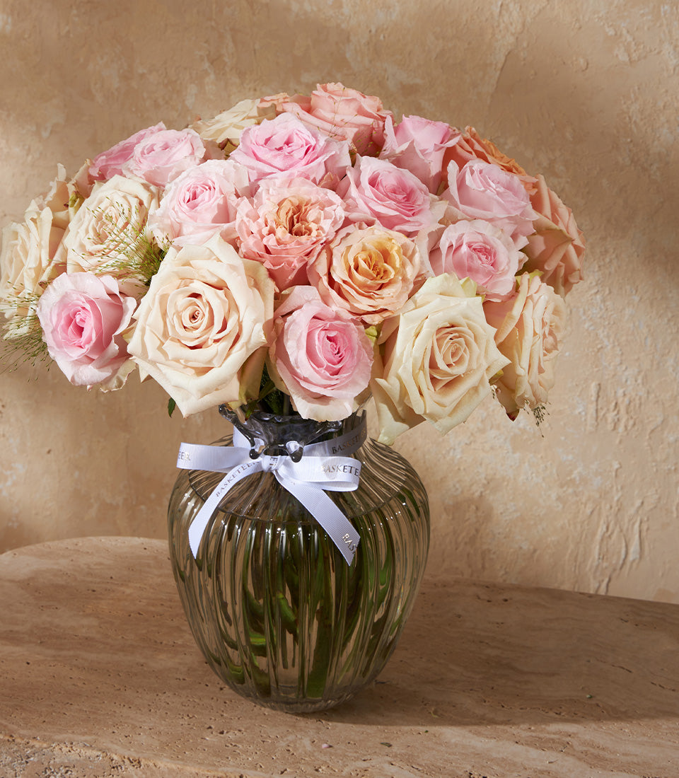 Premium pink and peach rose arrangement in ribbed glass vase with white ribbon bow