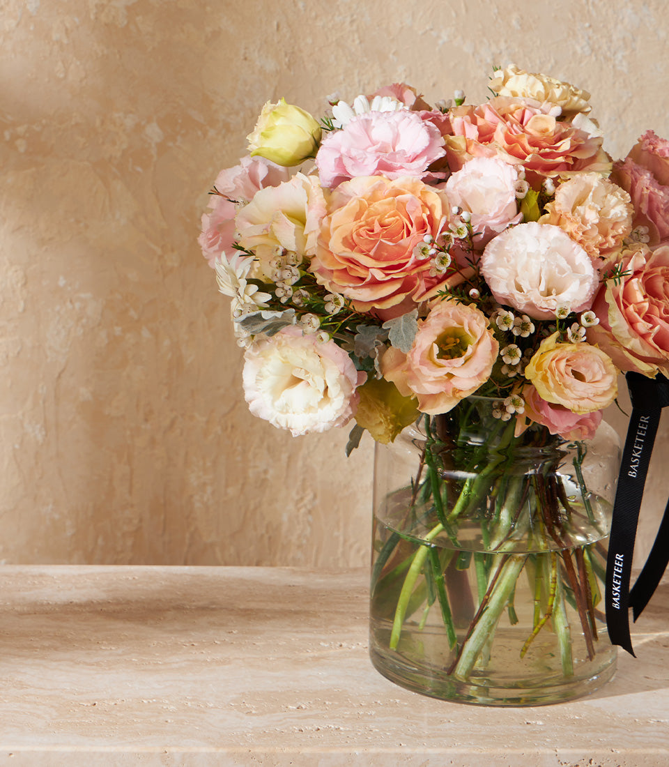 Peach and cream garden roses with lisianthus in clear glass vase, luxury fresh flower arrangement