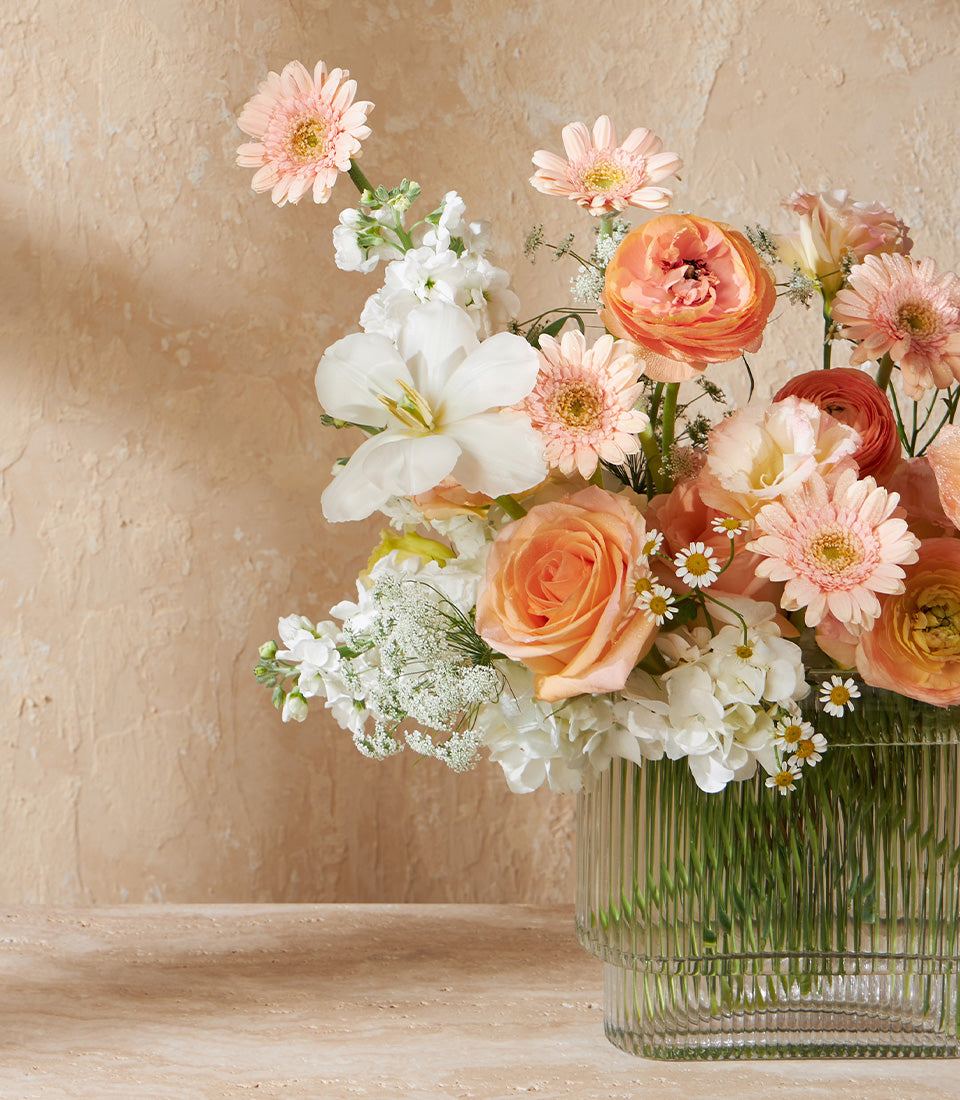 Peach garden roses and white lilies in ribbed glass vase arrangement