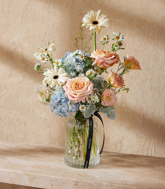 Radiant Harmony pastel floral vase arrangement with white gerberas, blue hydrangeas, and peach roses