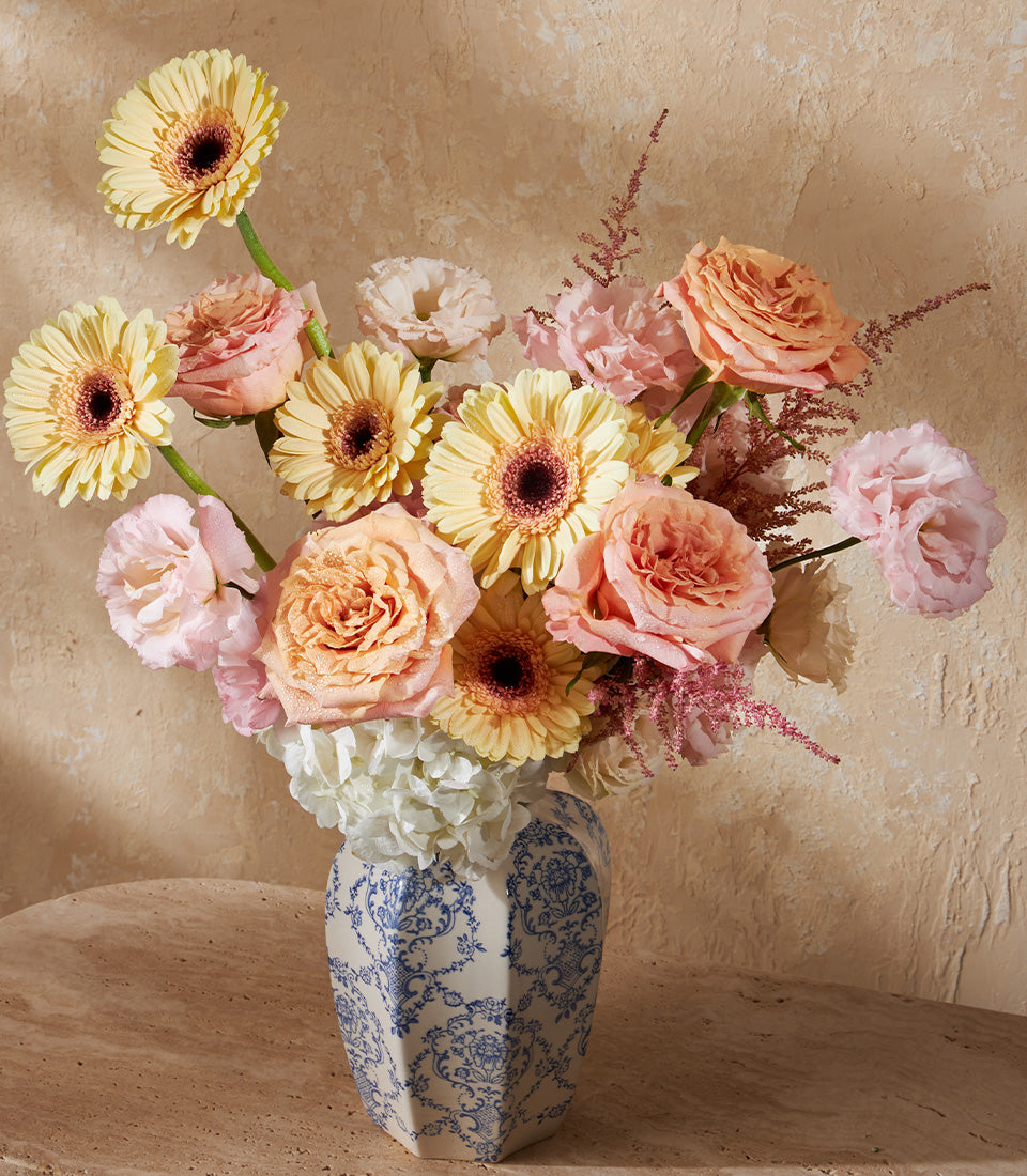 Golden Harmony luxury floral arrangement with yellow gerberas, roses, and hydrangeas in decorative blue and white ceramic