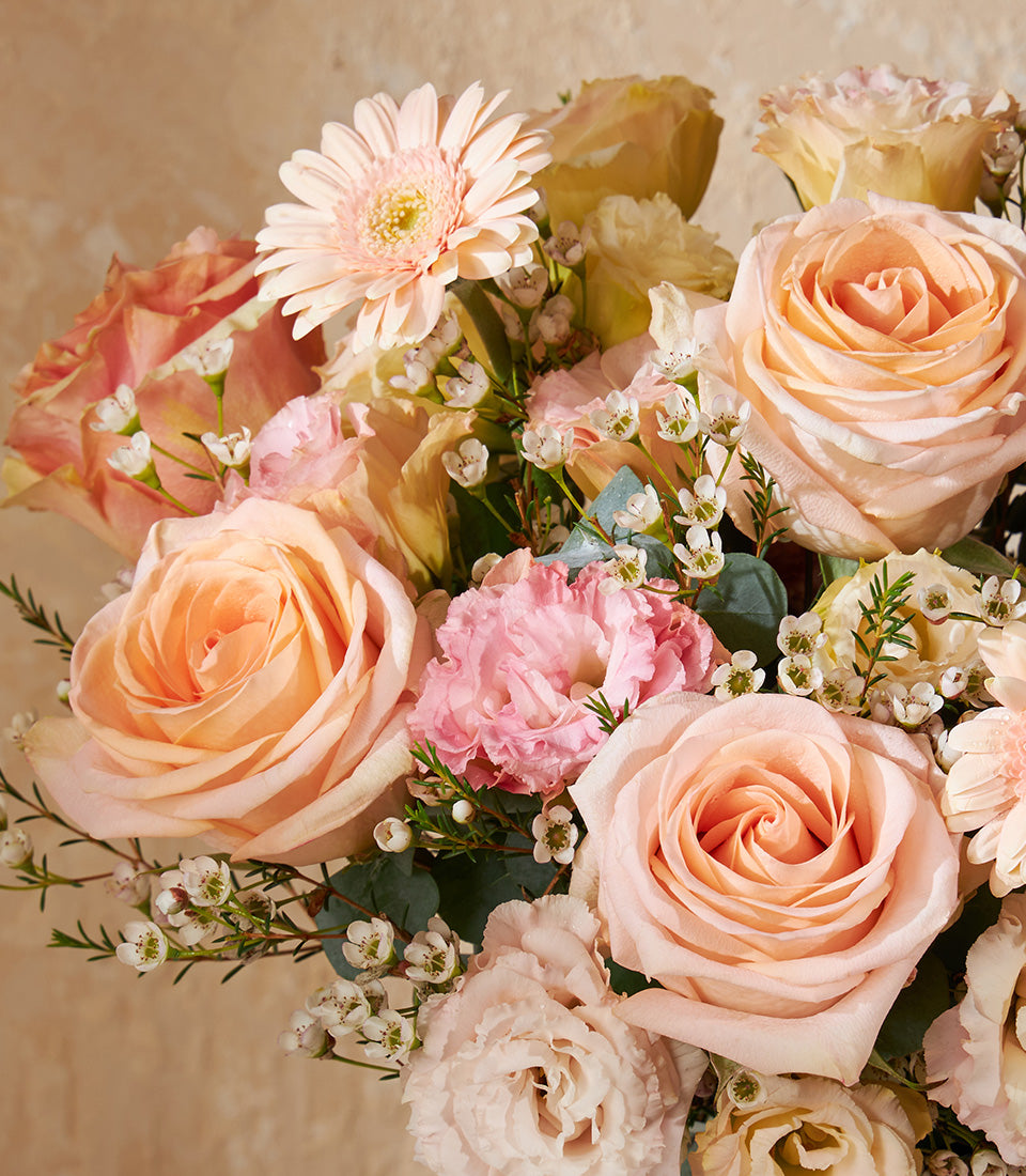 Peach and pink fresh rose bouquet with gerbera and lisianthus in elegant vase arrangement