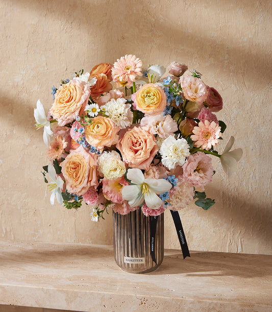 Peach and pink roses with ranunculus in ribbed metallic vase, pastel luxury flower arrangement