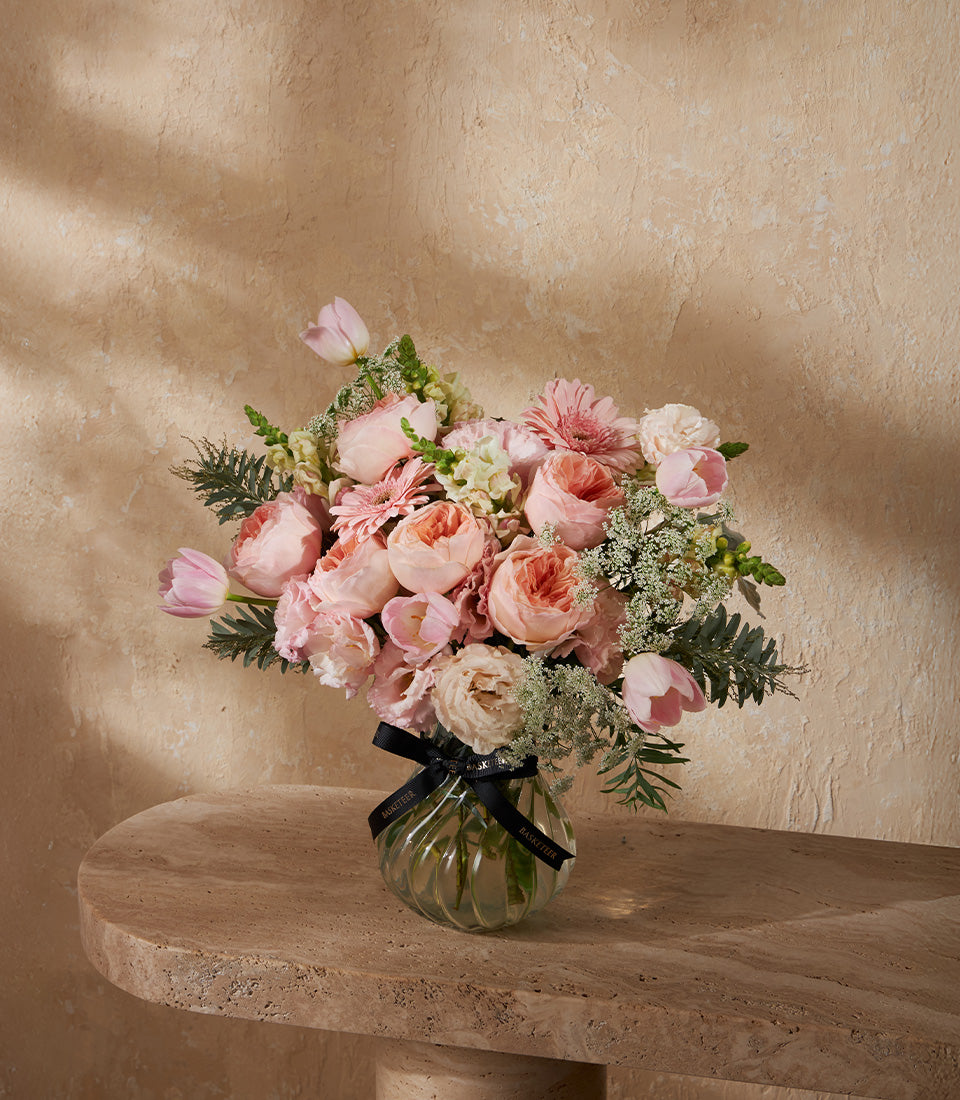 Pink rose and tulip bouquet in clear glass Juliet Elegance vase with green foliage and white accents
