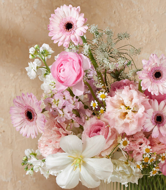 Pink and white fresh flower bouquet with roses, ranunculus, and gerberas in elegant glass vase