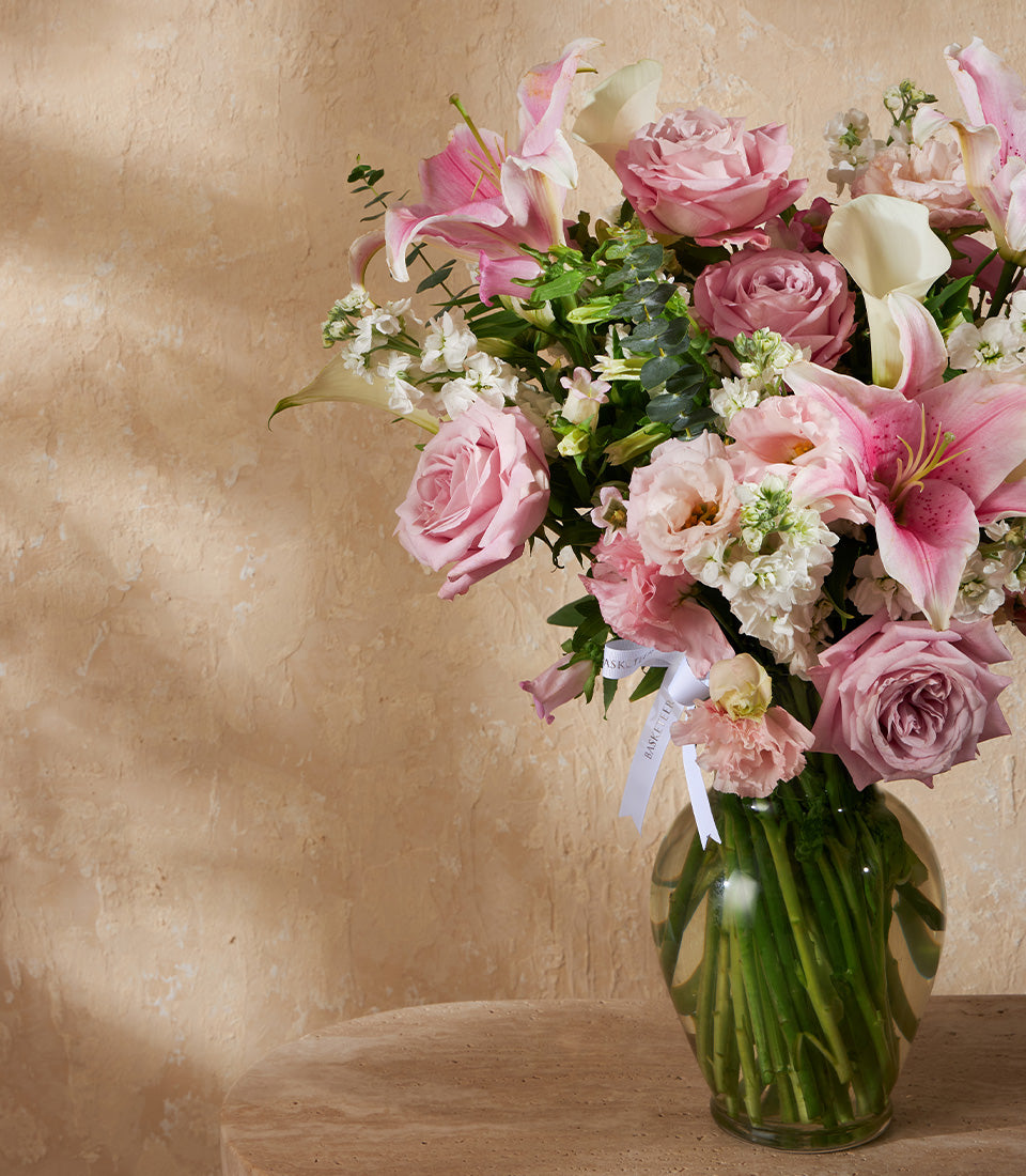 Pink and white fresh flower arrangement with lilies and roses in clear glass vase