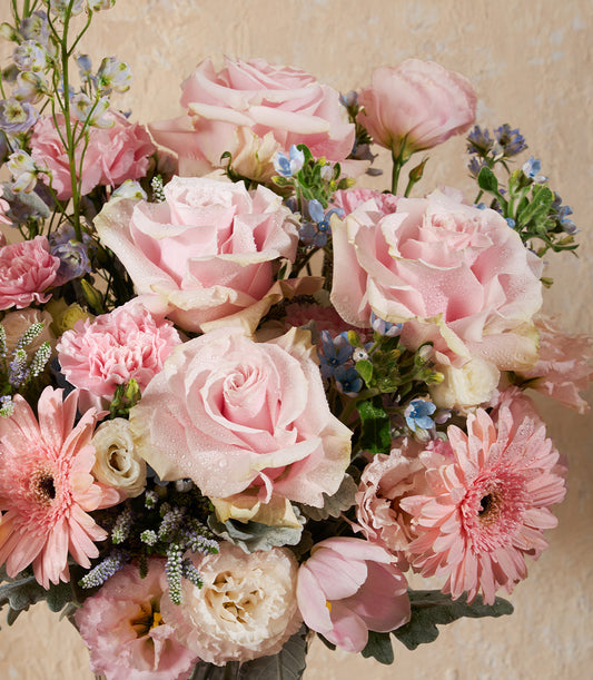 Pink roses, gerbera daisies, and light blue filler flowers in a fresh luxury bouquet