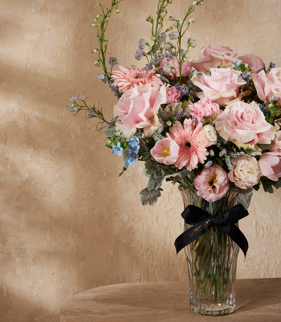 Pink rose and gerbera daisy arrangement in ribbed glass vase with black satin ribbon