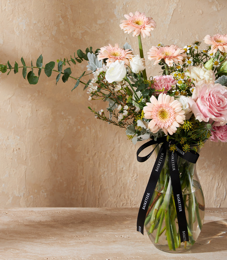 Light pink gerbera daisies and roses with eucalyptus in clear glass vase, congratulations flower gift