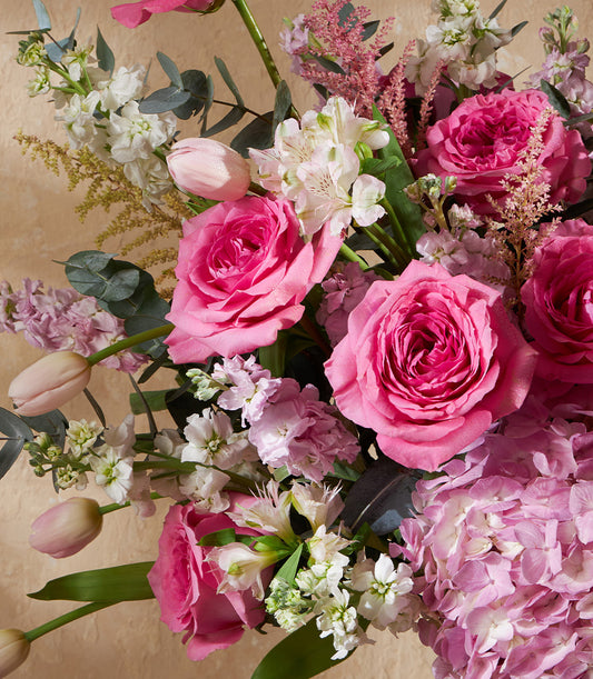 Pink and white roses with hydrangea, tulips, and filler flowers in a lush vase arrangement