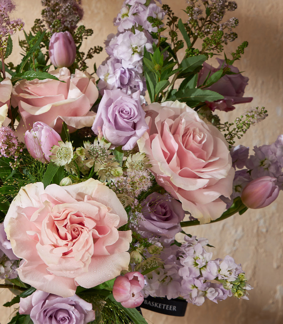 Pink and lavender roses with tulips in fresh vase arrangement, luxury gift hamper with ribbon detail
