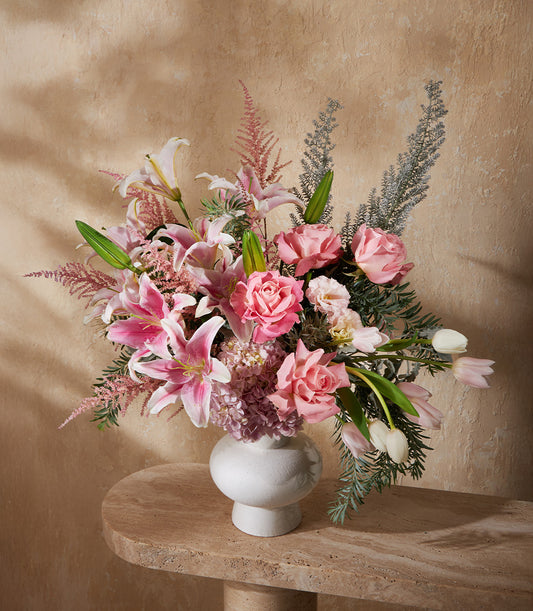 Blush pink and white floral arrangement with lilies, roses, hydrangeas in textured white ceramic vase