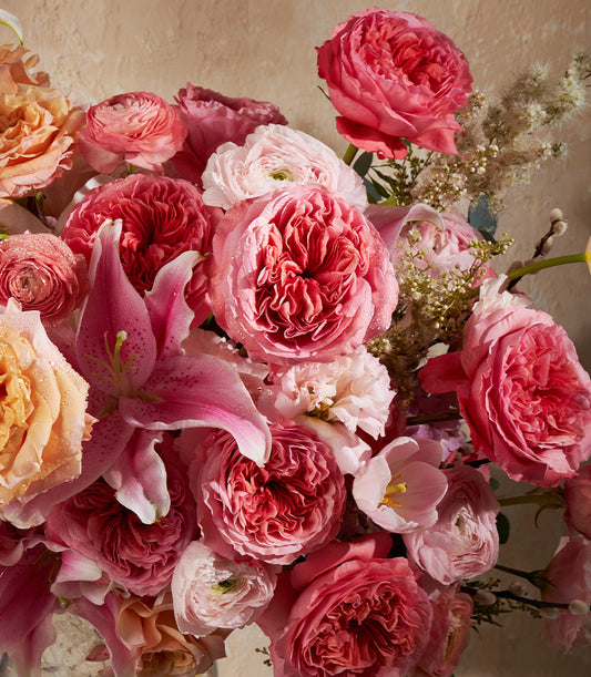 Radiant pink and peach garden roses with lily in lush vase arrangement