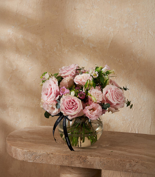 Pink rose mini arrangement in clear glass vase with white filler flowers and green foliage