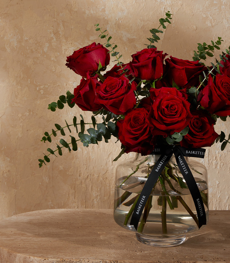 Deep red roses with eucalyptus in clear glass vase, fresh flower arrangement for gifting