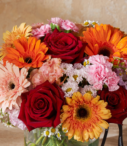 Vibrant Symphony fresh flower vase with red roses, gerberas, and carnations in warm tones