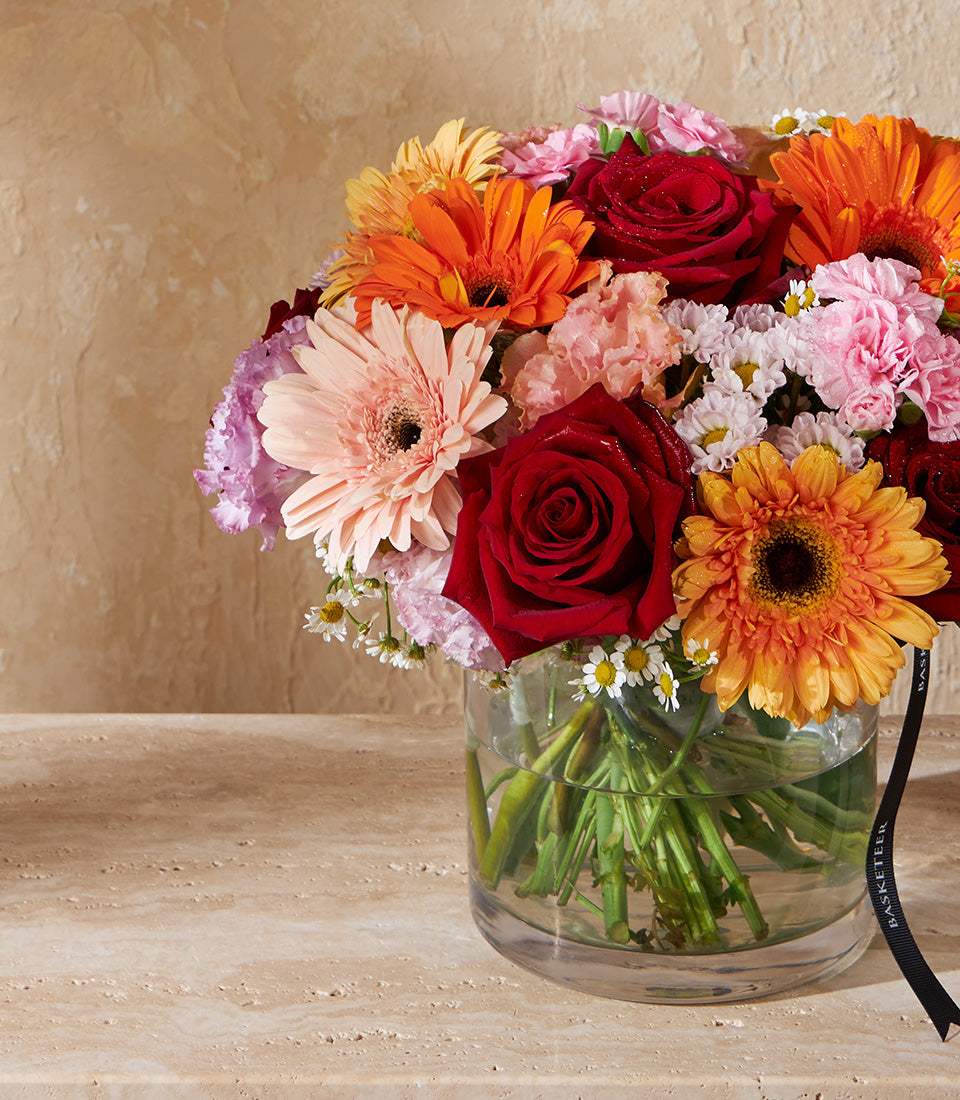 Vibrant fresh flower arrangement with roses, gerberas, and carnations in clear glass vase