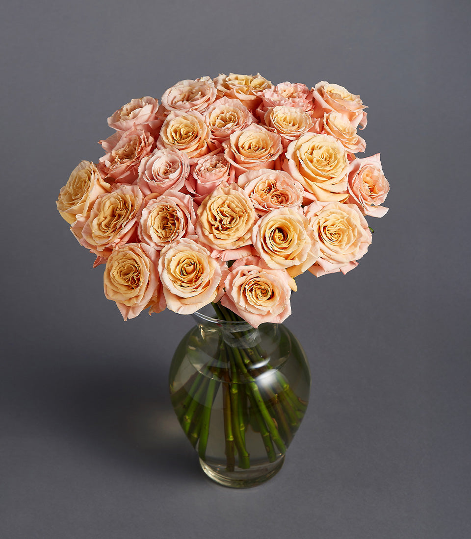 Peach and golden-yellow roses in clear glass vase, luxurious two-dozen arrangement for gifting