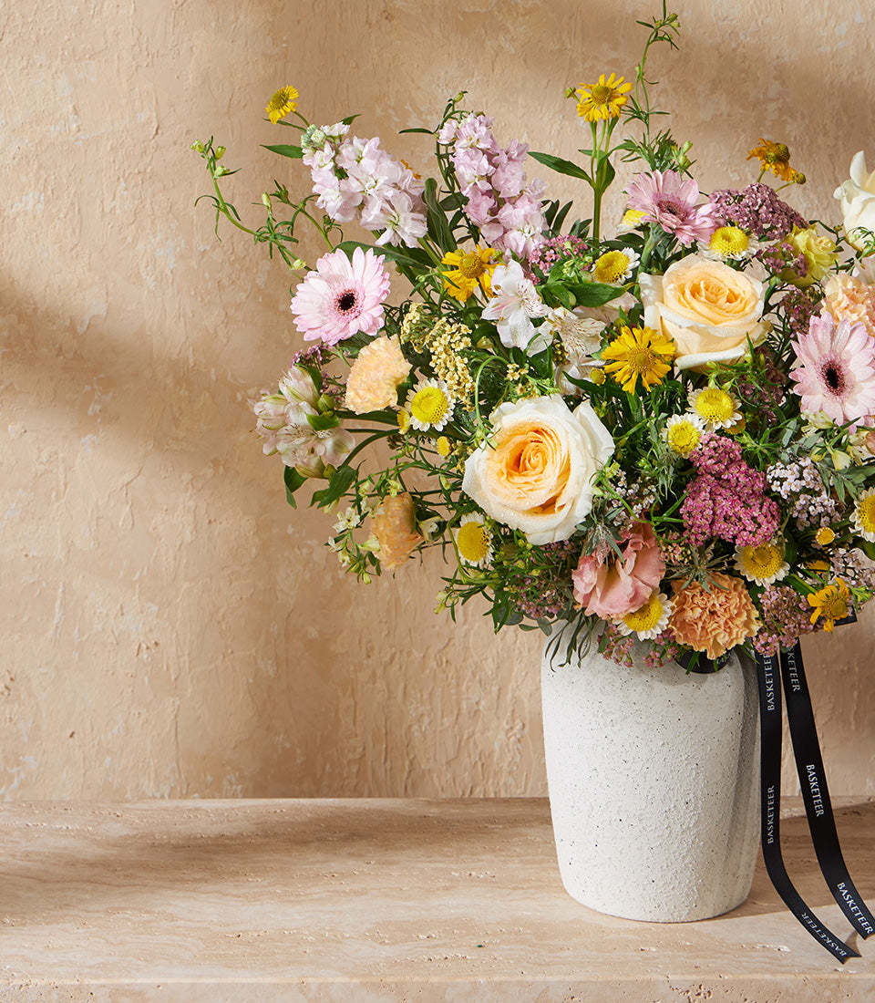 Pastel Garden Symphony floral arrangement with pink gerberas, roses and daisies in textured white vase