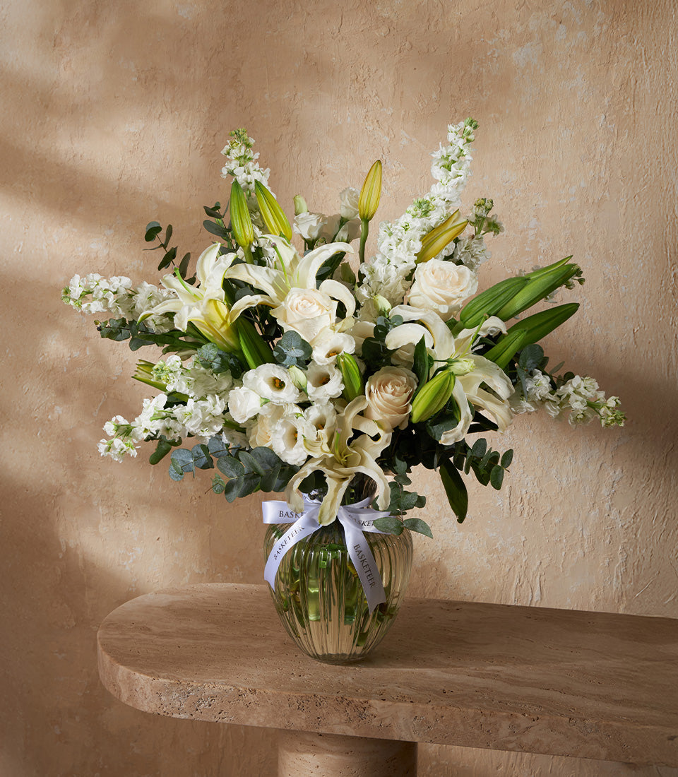 Elegant white lily vase arrangement with roses and eucalyptus in ribbed glass