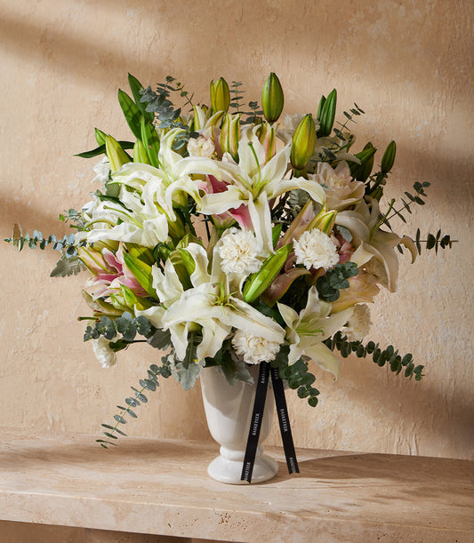 Elegant white lily and carnation arrangement in fluted ceramic vase with eucalyptus greenery